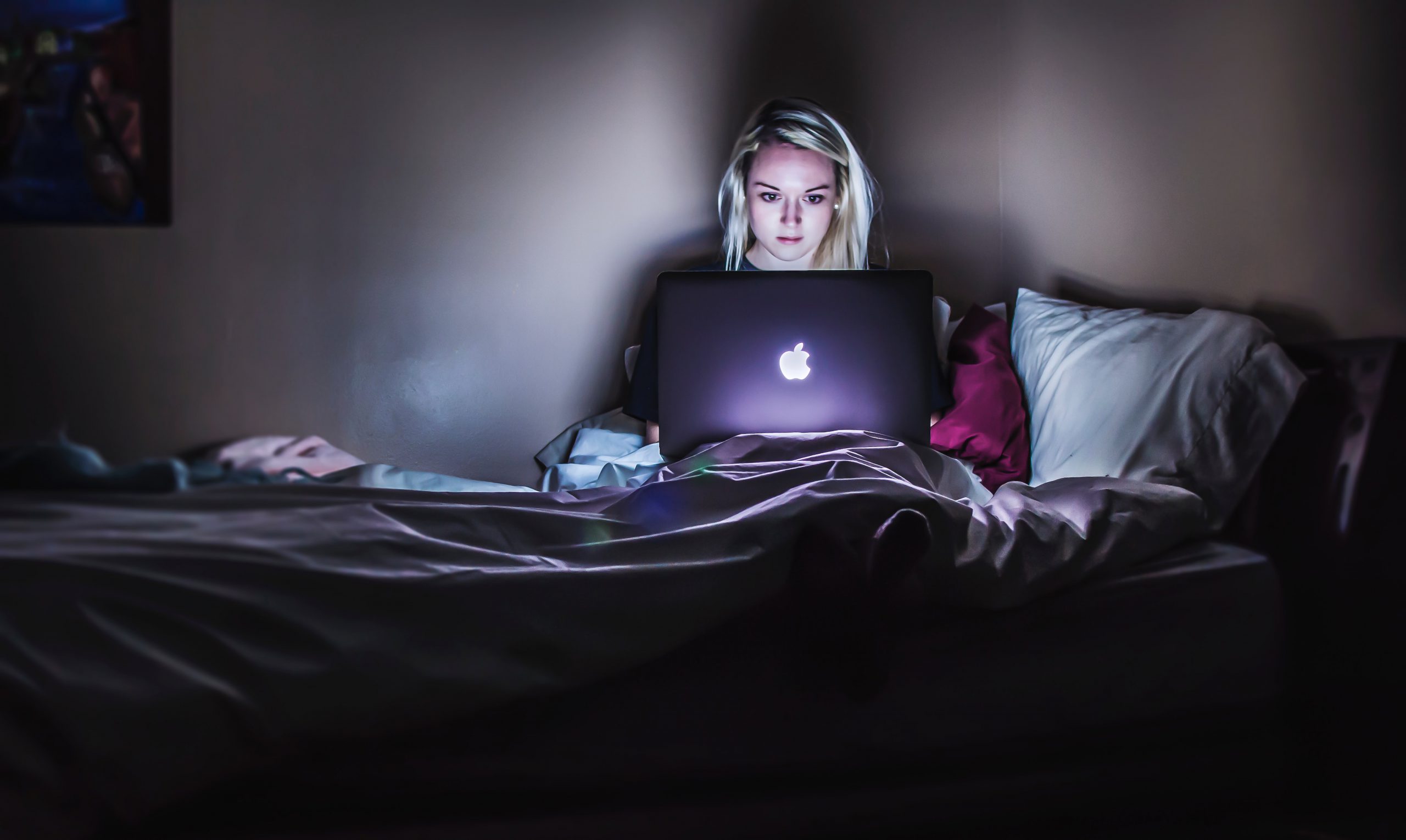 woman sitting on a bed with a laptop